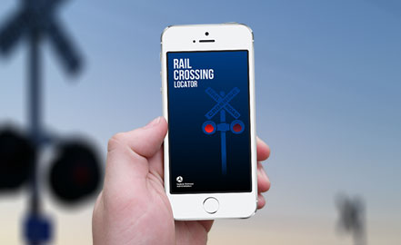 Cận cảnh điện thoại thông minh hiển thị Thiết bị định vị đường ray xe lửa. Nền là hình ảnh mờ của một giao lộ đường sắt.